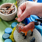 Child engaging in hands-on play with animal figures and natural materials in a water-themed learning setup
