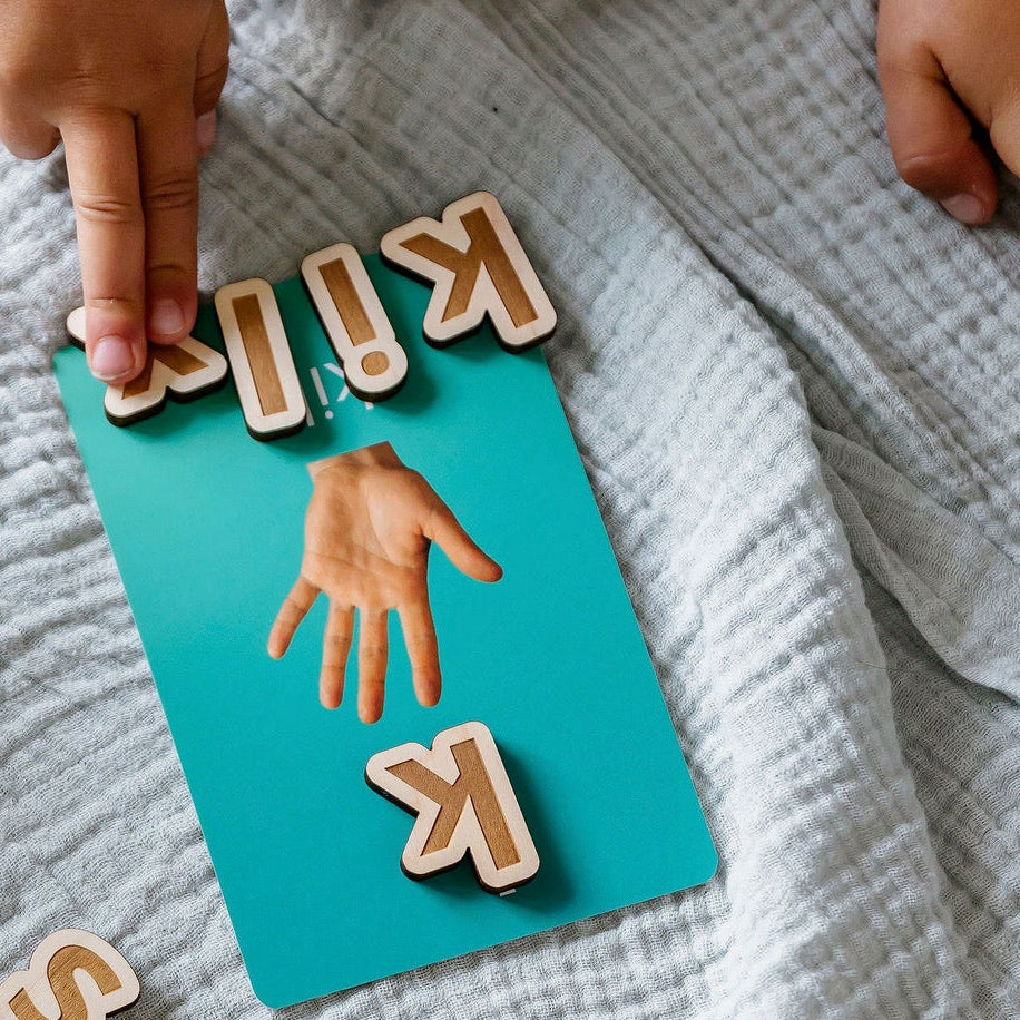 Child using Living Language Alphabet cards and wooden letters for hands-on word building and language learning